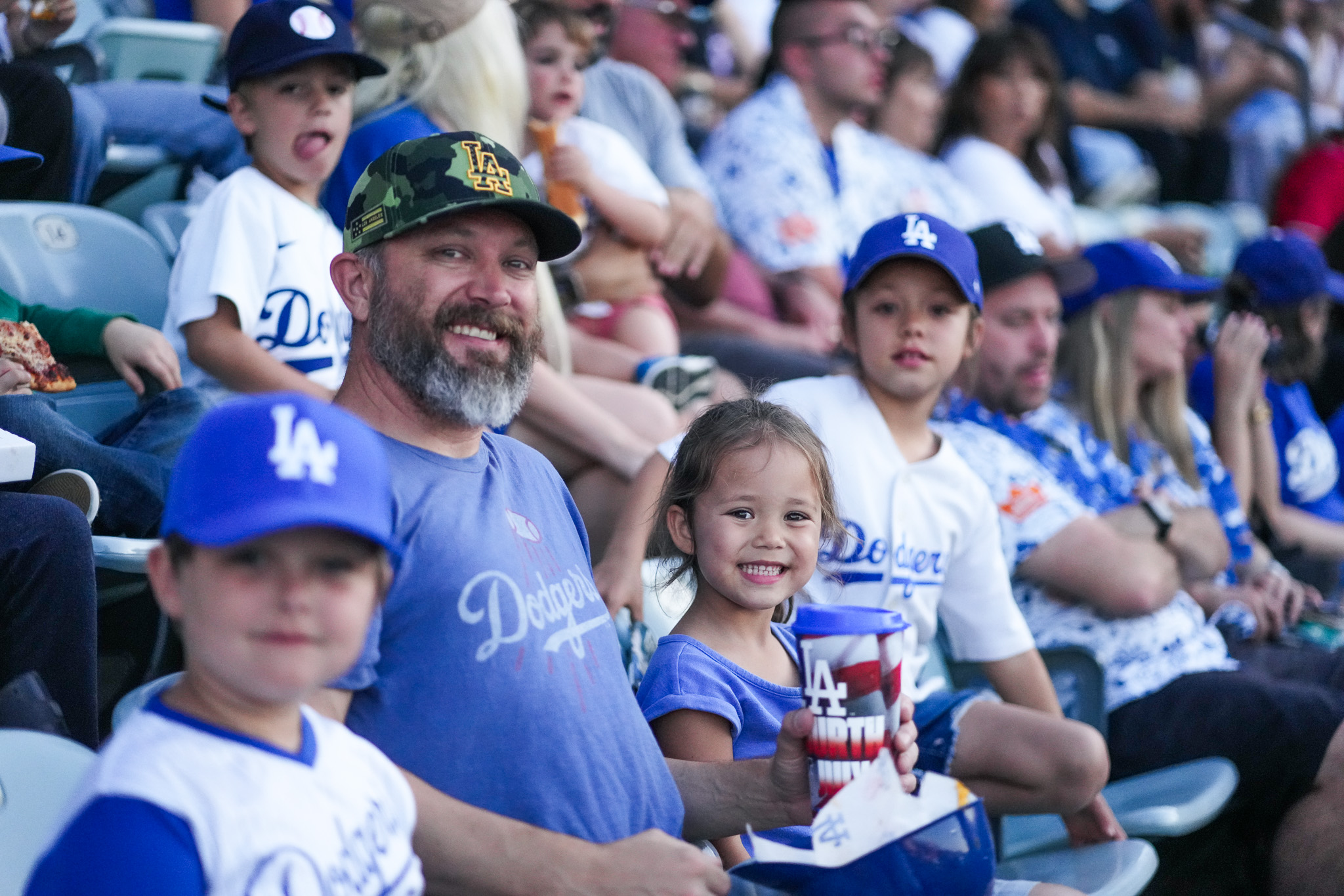 Dad and daughter in Dodgers gear smiling in the stands